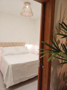 伊塔卡雷Flat Canto dos Pássaros的一间卧室配有一张床和盆栽植物