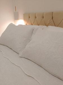 伊塔卡雷Flat Canto dos Pássaros的一张带白色床单和灯的未铺好的床