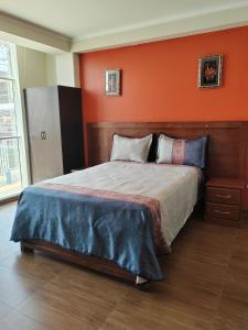 塔克纳Hostal Bryan的一间卧室配有一张橙色墙壁的床