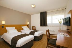 南特塞祖尔阿菲尔南特杜克布列塔尼酒店的酒店客房设有两张床和一张桌子。