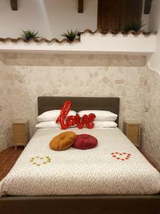 巴罗尼西Setteabbracci Suite & Apartments的一张带两个枕头的床,上面有“爱”字