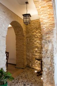 麦地那西多尼亚Hotel Tugasa Casa Palacio Medina Sidonia的石墙和高光灯的房间