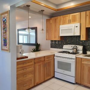 拿骚Ocean Breeze Villa 242的厨房配有木制橱柜和白色炉灶烤箱。