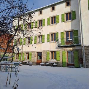 Odeillo-ViaLe Grenier des Moineaux的一座带绿色百叶窗和庭院的建筑
