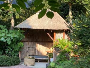 布拉里克姆De Schuilhoek Private Guesthouse的一个带长凳和茅草屋顶的小小屋