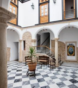 麦地那西多尼亚Hotel Tugasa Casa Palacio Medina Sidonia的庭院设有黑白的格子地板