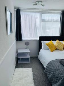 艾尔斯伯里Aylesbury Apartment for Contractors and Holidays的一间卧室配有一张带黄色枕头的床和一扇窗户