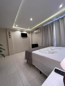 阿拉亚尔-杜卡布Pousada Arraial Tropical的一间卧室配有一张大床和电视
