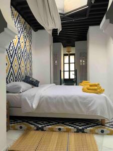 艾西拉Asilah * Dar Badiaa * Riad vue sur l’Atlantique的一间卧室配有一张大床,床上配有黄色毛巾