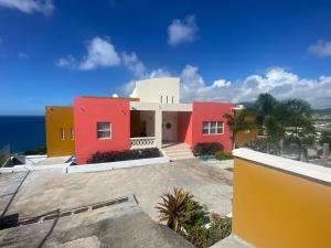巴斯特尔La Vue de Basseterre Apartments - Luxury in Bird Rock的一座红色和黄色的房子,背景是大海