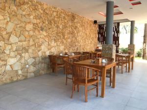 吉利特拉旺安Soda Resort Gili Trawangan的一间设有木桌和椅子的餐厅以及石墙
