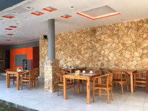 吉利特拉旺安Soda Resort Gili Trawangan的一间设有木桌和椅子的餐厅以及石墙