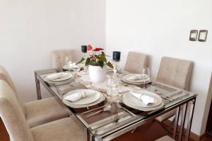 利马Apartment 4 Rent - Av San Borja Norte Cdra 8的玻璃桌,带板子和花瓶