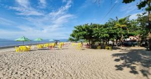 安格拉杜斯雷斯Pousada del Sole的海滩上海滩上沙滩上摆放着黄色椅子和遮阳伞