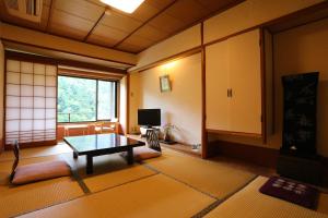京都Momijiya Honkan Takaosansou的客厅配有桌子和电视