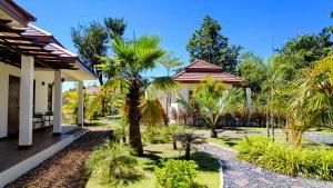 乌隆他尼Isan Golf & Adventure Hotel的一座带棕榈树庭院的房子