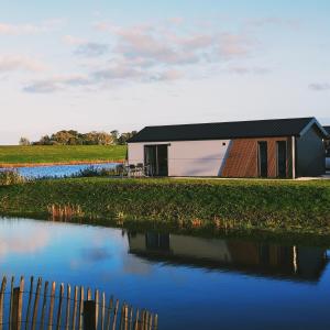 坎彭Chalet IJssel Eilanden Kampen Waterfront Airco的河边的黑屋顶房子