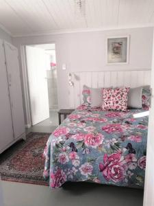海德堡Rose Cottage AtTheDairyShed的一间卧室配有一张带花卉床罩的床