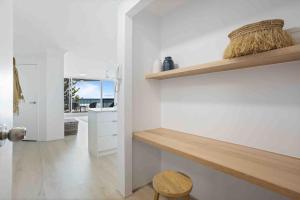 黄金海岸Beachfront Luna Apartment的厨房拥有白色的墙壁和木制架子