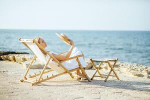 海法Domus Bat Galim Hotel的躺在沙滩上椅子上的女人