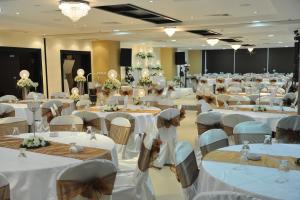 拉马拉Caesar Hotel Ramallah的一个带白色桌椅的大型宴会厅