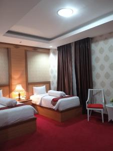 DukuGrand Buana Lestari Hotel的酒店客房,配有两张床和椅子