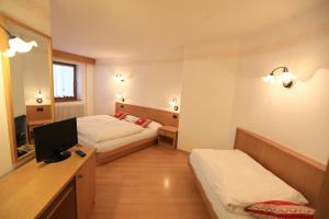 阿尔巴迪卡纳泽伊Appartamenti Arnica的酒店客房设有两张床和一张书桌及电视