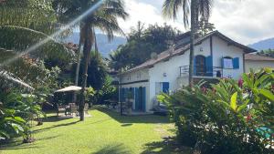 博西坎加Hospedaria do Marquês的白色的房子,有蓝色的门和棕榈树