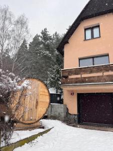 ChyšeChata s panoramatickou saunou的坐在房子外的雪中的一个木桶