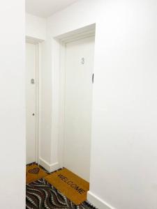 伦敦Studio Apartment in Seven Sisters的一条带白色门和地毯的走廊