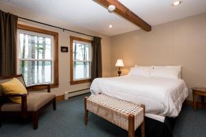 LovellThe Lodge at Pleasant Point的一间卧室配有一张床和一把椅子,还有两个窗户