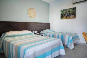 埃斯孔迪多港Hotel Camino Del Sol的一间卧室配有两张带条纹床单的床