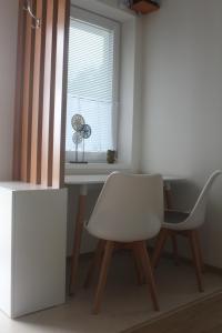科瓦科瓦Spa Apartmán Kováčová的窗户客房内的白色椅子和书桌