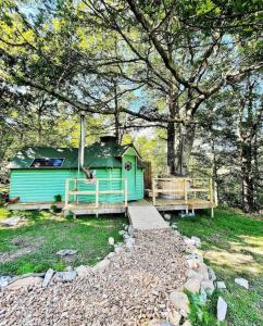 巴茅思Woodland Cabin with Hot tub & log burner的树旁的一座带桥的绿色房子