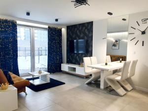 索斯诺维茨Konopnickiej 88 Cosy Apartment的客厅配有白色的桌椅和时钟