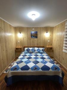 普孔Cabañas Rukafun 2的卧室配有蓝色和白色的格子床