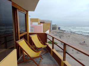AricaArica Surf & Beach House的两把黄色椅子坐在俯瞰着海滩的阳台上
