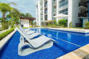 查梅Playa Caracol, beach happy的一座带躺椅的游泳池位于大楼旁