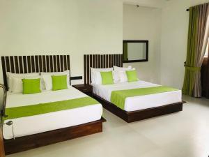 阿努拉德普勒Divine Villa的配有绿色枕头的酒店客房内的两张床