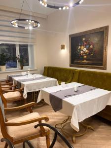 阿克托比阿克托比达斯坦酒店的餐厅设有桌椅,墙上挂有绘画作品