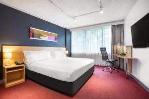 墨尔本墨尔本机场假日酒店的酒店客房设有一张大床和一张书桌。