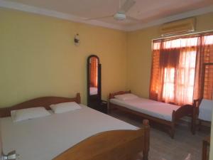 波隆纳鲁沃Green Parrot Family Resort的一间卧室设有两张床和窗户。