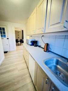 奥尔堡aday - Modern 1 Bedroom Charming Central Apartment with Public Parking的厨房配有白色橱柜和水槽