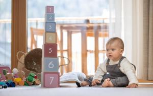斯拉德明das bleibt Alpine Suites的坐在玩具组旁边的地板上的一个婴儿