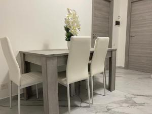 塞里亚泰Casa Dea 3的餐桌,配有白色椅子和花瓶