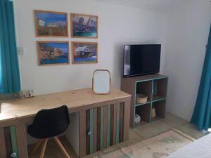 CalodyneKailani的客房设有一张桌子、一台电视和一张桌子及椅子