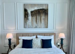 迪拜Luxurious Beachfront Apartment的一间卧室配有一张带两盏灯和一幅画的床铺