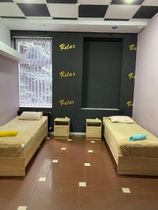 PavlohradГРК РЕЛАКС的墙上有黄色写字的房间里,有两张床