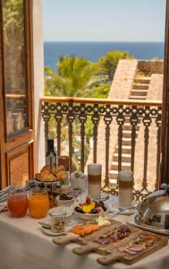 伊维萨镇Mirador de Dalt Vila-Relais & Chateaux的阳台上摆放着食品和饮料的桌子