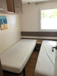 Saint-AugustinMobilhome 4/6 personnes proche La Palmyre, Royan的小房间设有两张床和窗户